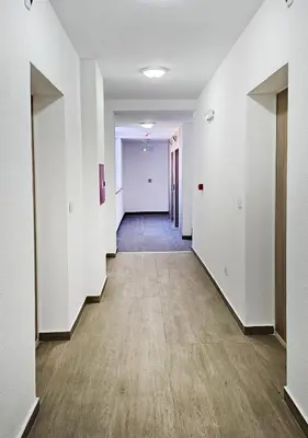 an empty hallway with white walls and wood floors at Cozy Mountain Apartment VIDIK in Kopaonik