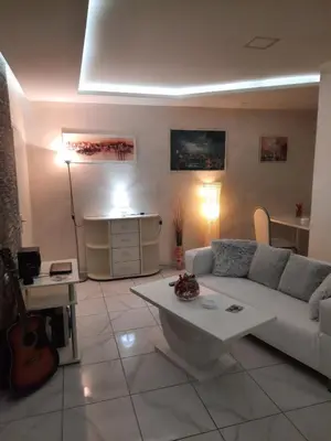a living room with a white couch and a guitar at Center Apartment in Niš