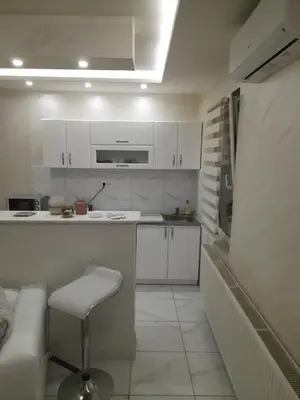 a kitchen with white cabinets and a stool in it at Center Apartment in Niš