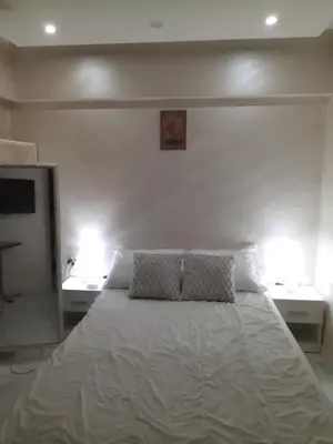 a bedroom with a white bed with two night stands at Center Apartment in Niš