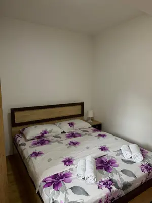 a bed with white towels and purple flowers on it at Olimp apartmani Sokobanja in Soko Banja