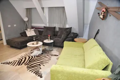 a living room with a green chair and a couch at Apartman Family Konaci in Kopaonik