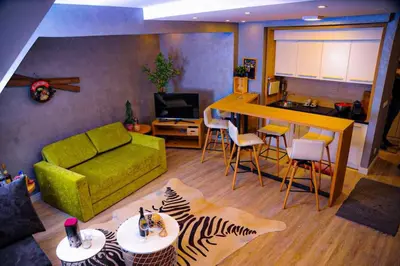 a living room with a green couch and a kitchen at Apartman Family Konaci in Kopaonik