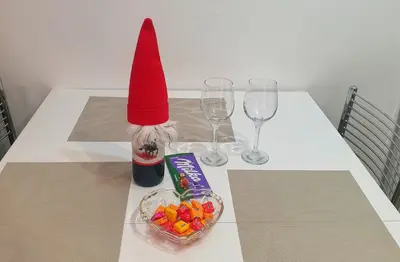 a red hat on a table with wine glasses and a bowl of candy at Park app in Vrnjačka Banja