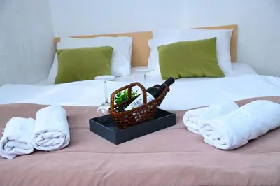 a bed with towels and glasses and a basket on it at ApartHotel Kopaonik in Brzeće
