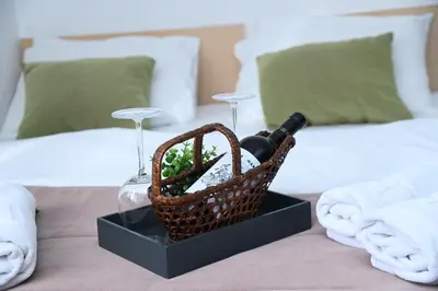 a basket with wine glasses and a bottle on a bed at ApartHotel Kopaonik in Brzeće