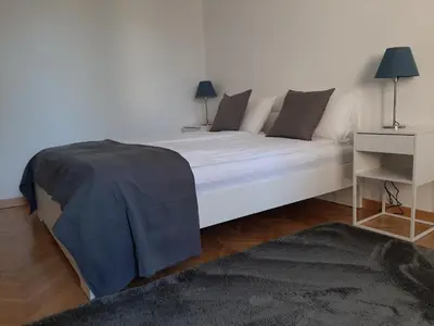 a large white bed in a white room with a table at Vrnjci House in Vrnjačka Banja