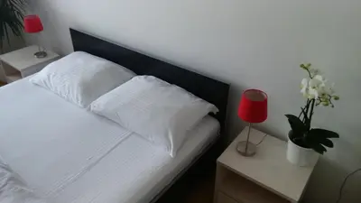 a bedroom with a white bed with a red lamp and flowers at Vrnjci House in Vrnjačka Banja