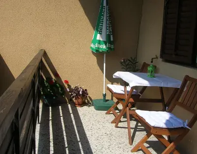 a patio with a table and a green umbrella at Vrnjci House in Vrnjačka Banja