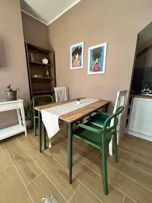 a dining room with a table and green chairs at San apartman in Vrnjci