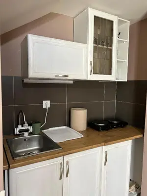 a kitchen with white cabinets and a sink at San apartman in Vrnjci