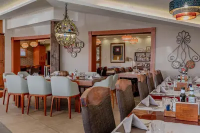 a restaurant with tables and chairs and a chandelier at Apartman Kopaonik u Kraljevim Čardacima in Kopaonik