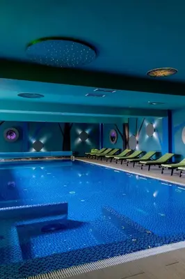 a swimming pool with blue walls and green seats at Apartman Kopaonik u Kraljevim Čardacima in Kopaonik