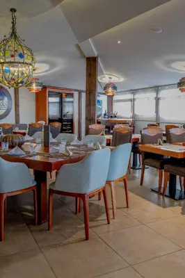 a restaurant with wooden tables and chairs and a chandelier at Apartman Kopaonik u Kraljevim Čardacima in Kopaonik