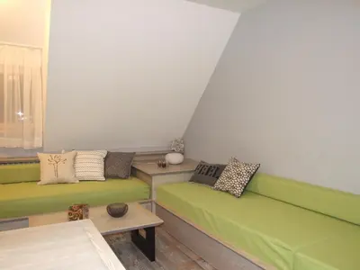 a living room with green couches and a table at Apartmani Kopaonik Centar Maglic in Kopaonik