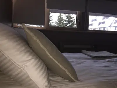 a bed with two pillows on it with two windows at Apartmani Kopaonik Centar Maglic in Kopaonik