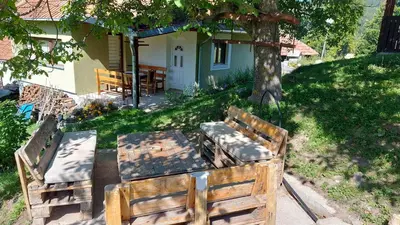 a pair of benches sitting in the grass near a house at Nacionalna kuca Krstojevic in Raška