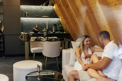 a man and a woman sitting on a couch with a baby at Luxurious cabin for couples with hot tub lake view in Aleksinac