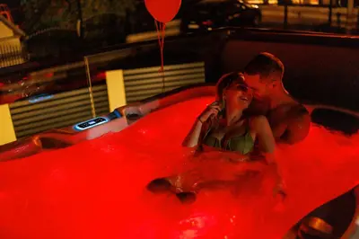 a man and a woman sitting in a hot tub at Luxurious cabin for couples with hot tub lake view in Aleksinac