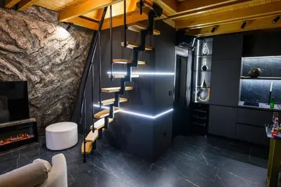 a staircase in a room with a stone wall at Luxurious cabin for couples with hot tub lake view in Aleksinac