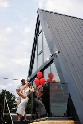 a bride and groom standing outside of a house with red balloons at Luxurious cabin for couples with hot tub lake view in Aleksinac