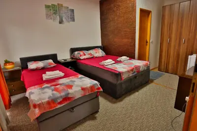 two beds in a hotel room with red sheets at Smeštaj Đorić in Leskovac