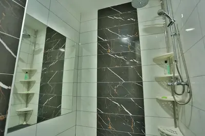 a bathroom with a shower with a black marble wall at Smeštaj Đorić in Leskovac