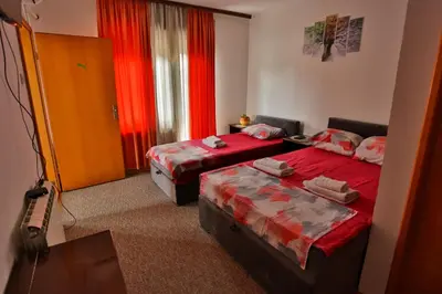 two beds in a room with red curtains at Smeštaj Đorić in Leskovac