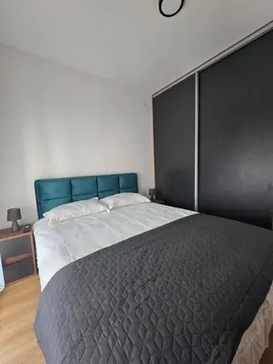 a bedroom with a large bed with a blue headboard at Sunny lux apartman in Vrnjačka Banja