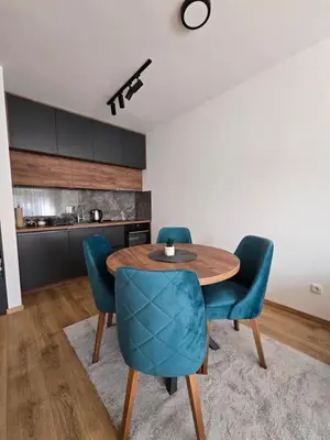 a kitchen and dining room with a wooden table and blue chairs at Sunny lux apartman in Vrnjačka Banja