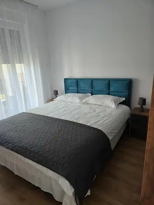 a large bed with a blue headboard in a bedroom at Sunny lux apartman in Vrnjačka Banja