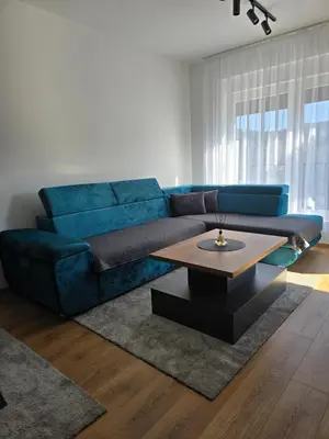 a living room with a blue couch and a coffee table at Sunny lux apartman in Vrnjačka Banja