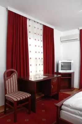 a room with a desk and a bed and a television at Vila Lux Milikic in Kraljevo