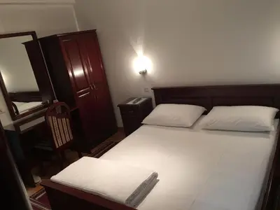 a small bedroom with a bed and a chair at Vila Lux Milikic in Kraljevo