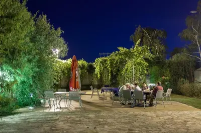 a group of people sitting at tables and chairs at night at Vila Lux Milikic in Kraljevo
