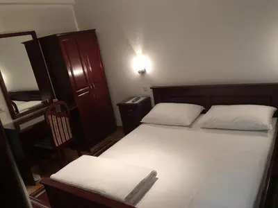 a small bedroom with a bed and a chair at Vila Lux Milikic in Kraljevo
