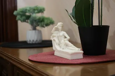 a statue of a man sitting on a table next to a plant at Apartmani Varos & Restaurant in Pirot