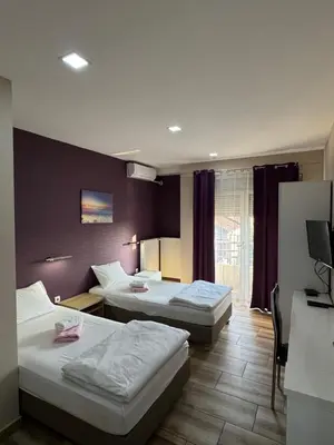 a hotel room with three beds and a window at Bed & Coffee LUKAS Krusevac in Kruševac