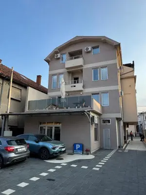 a building with cars parked in a parking lot at Bed & Coffee LUKAS Krusevac in Kruševac