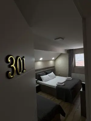 a bedroom with two beds and a clock on the wall at Bed & Coffee LUKAS Krusevac in Kruševac