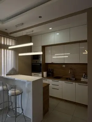 a kitchen with white cabinets and a bar with stools at Bed & Coffee LUKAS Krusevac in Kruševac