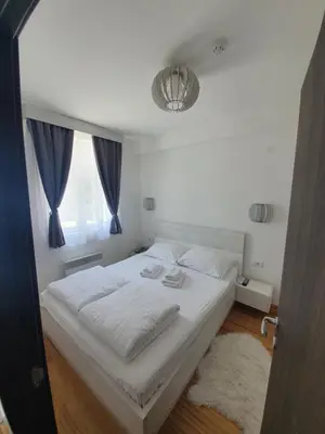 a bedroom with a large white bed with a window at Tri srca - Kraljevi Cardaci in Kopaonik