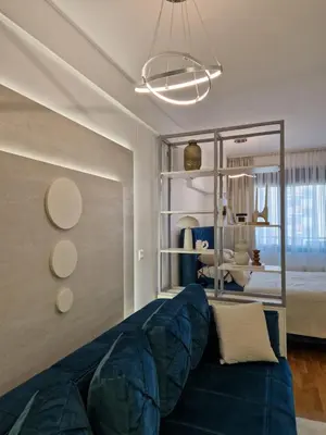 a living room with a blue couch and a bedroom at APARTMAN PLAVA LAGUNA -Crnjanski in Jagodina