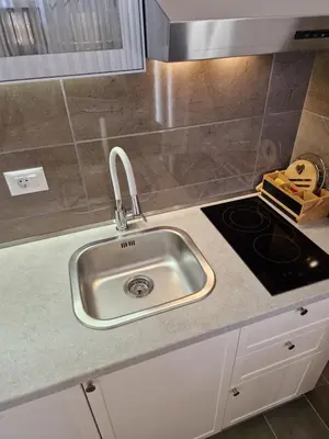 a kitchen counter with a sink and a stove at APARTMAN PLAVA LAGUNA -Crnjanski in Jagodina