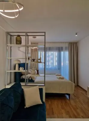 a bedroom with a bed and a couch in a room at APARTMAN PLAVA LAGUNA -Crnjanski in Jagodina