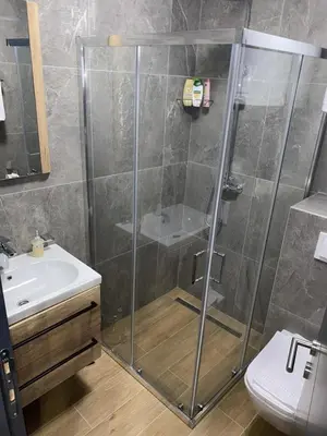 a bathroom with a shower with a sink and a toilet at Lawa Apartments Kopaonik in Cajetina