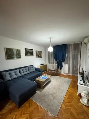 a living room with a blue couch and a table at Apartman Ristić in Pirot