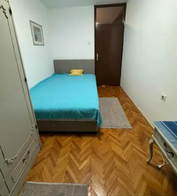 a small bedroom with a bed and a wooden floor at Apartman Ristić in Pirot