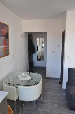a living room with a glass table and white chairs at Studio SimpaKop in Kopaonik