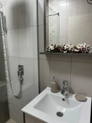 a bathroom with a sink and a shower with flowers at Apartment Mountain View Haven in Kopaonik